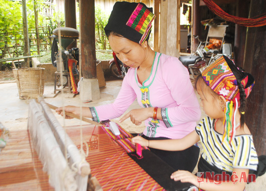 Chị Lô Thị Nhung (bản Khe Rạn) dạy cho con những thao tác đầu tiên của nghề  dệt thổ cẩm.